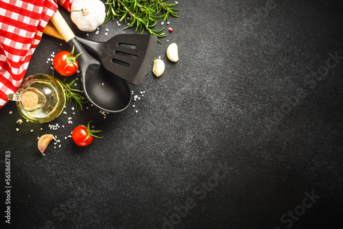 Food background on black. Herbs, spices and utensil for healthy cooking. Top view with copy space.