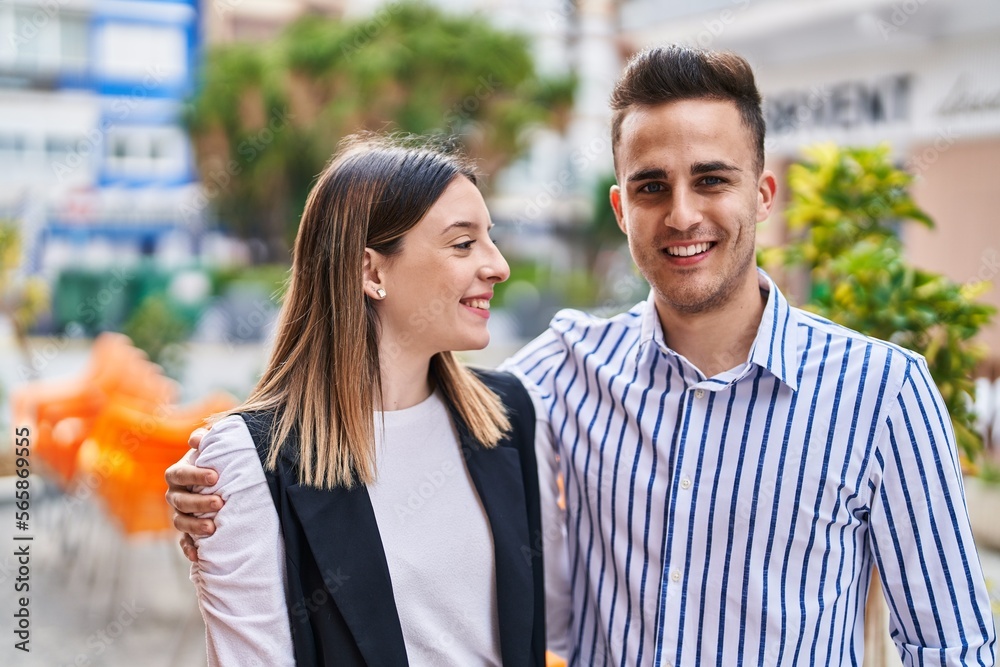 Naklejka premium Man and woman couple smiling confident hugging each other at street