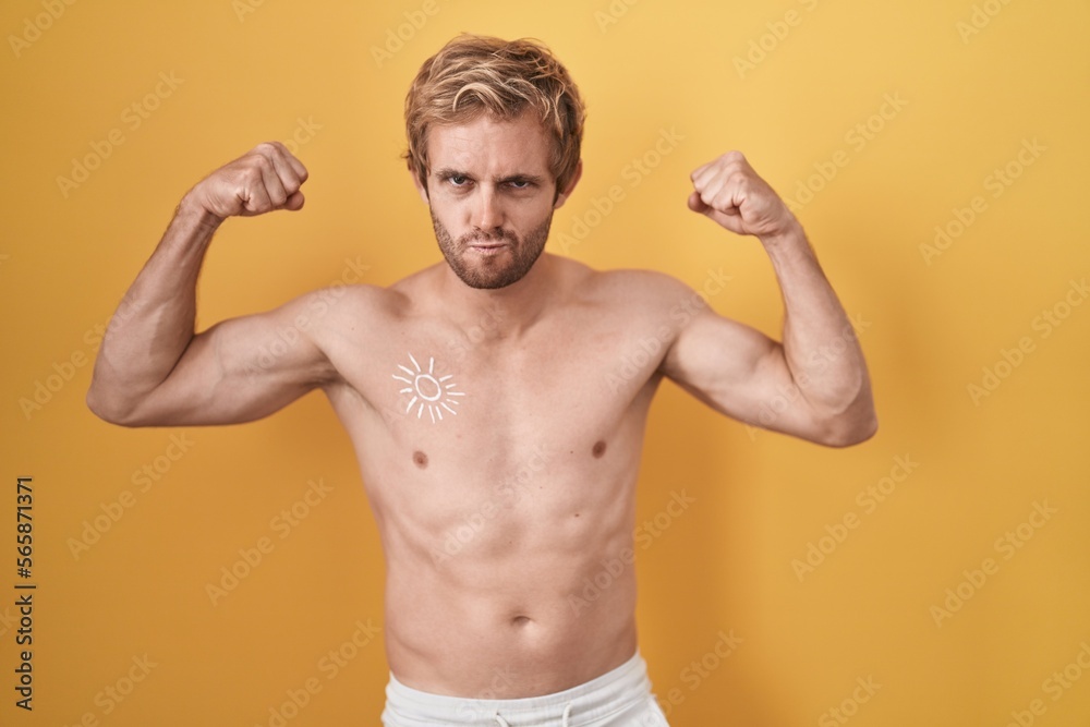 Fototapeta premium Caucasian man standing shirtless wearing sun screen showing arms muscles smiling proud. fitness concept.