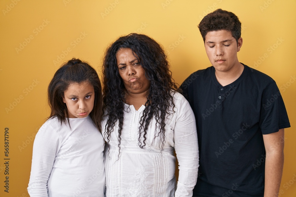 Family of mother, daughter and son standing over yellow background depressed and worry for distress, crying angry and afraid. sad expression. Family of mother, daughter and son standing over yellow background depressed and worry for distress, crying angry and afraid. sad expression.