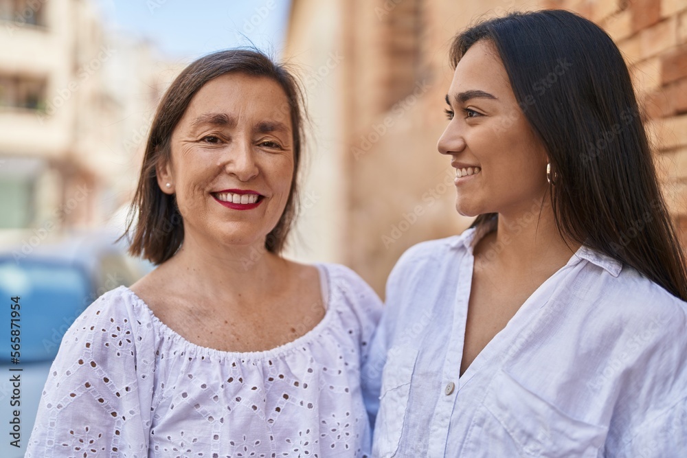 Two women mother and daughter smiling confident hugging each other at street