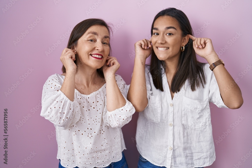 Hispanic mother and daughter together smiling pulling ears with fingers, funny gesture. audition problem Hispanic mother and daughter together smiling pulling ears with fingers, funny gesture. audition problem