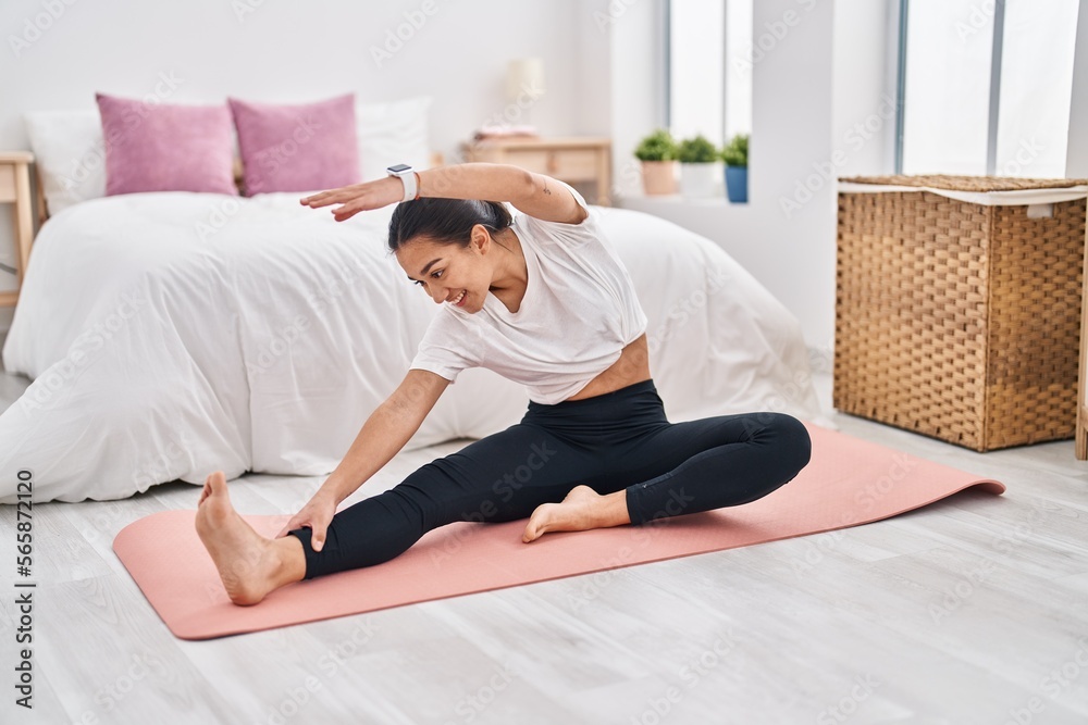 Young hispanic woman smiling confident stretching at bedroom