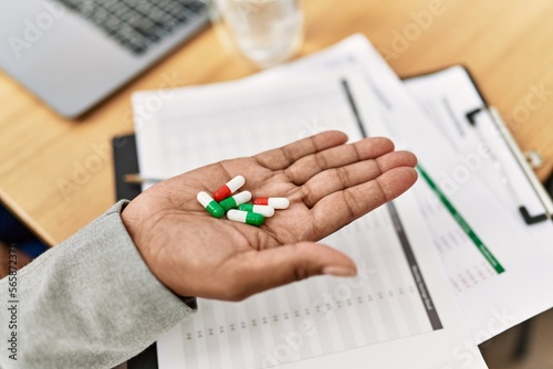 Senior african american woman business worker holding pills at office