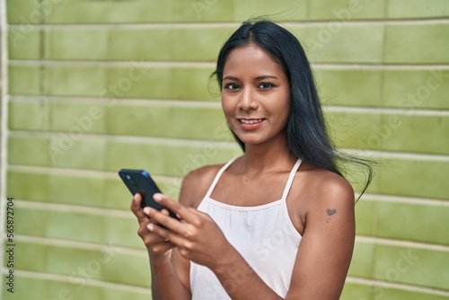 Young beautiful woman smiling confident using smartphone over isolated green background
