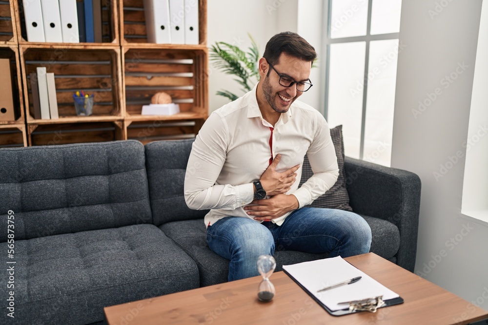 Young hispanic man with beard working at consultation office smiling and laughing hard out loud because funny crazy joke with hands on body. Young hispanic man with beard working at consultation office smiling and laughing hard out loud because funny crazy joke with hands on body.