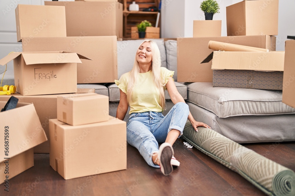 Young blonde woman smiling confident relaxed sitting on floor at new home Young blonde woman smiling confident relaxed sitting on floor at new home