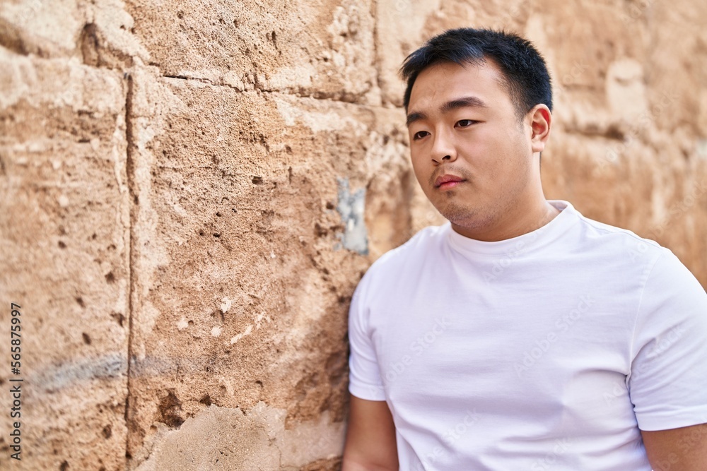 Young chinese man standing with relaxed expression at street Young chinese man standing with relaxed expression at street