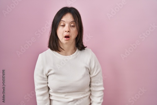 Woman with down syndrome standing over pink background looking sleepy and tired, exhausted for fatigue and hangover, lazy eyes in the morning. © Krakenimages.com