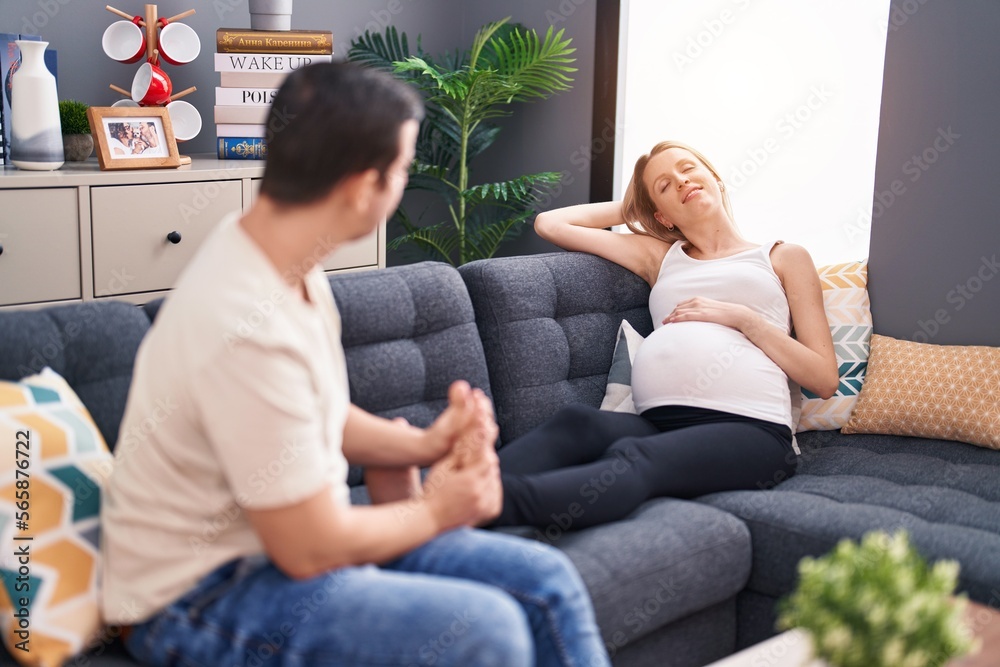 Man and woman couple expecting baby massaging feet at home Man and woman couple expecting baby massaging feet at home