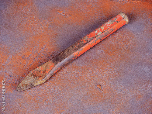 Old rusty stone chisel on a grunge background