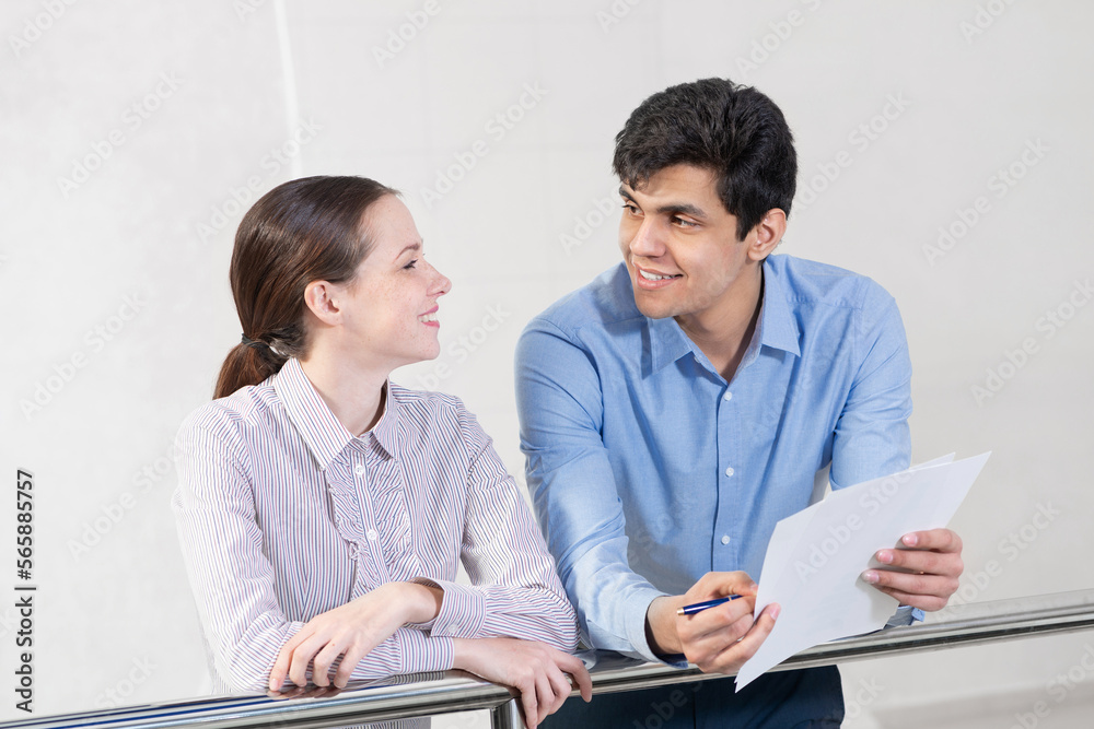 young woman and colleague discuss document young woman and colleague discuss document