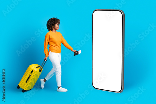 Excited young black woman traveller walking towards cell phone, mockup