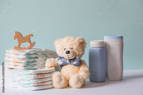 Obraz na płótnie Wooden toys, a bear in a bow tie, a stack of diapers, bottles without labels and baby supplies on the changing table