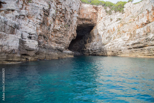 Landscape with pinewoods above limestone walls, scarps and a blue cave on Lokrum island in the Adriatic Sea with nits beautiful turquoise water near Dubrovnik, Croatia