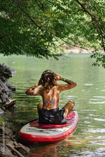 A pregnant woman sits on a sup and listens to music