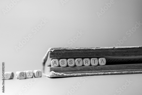 Assyria. Wooden cubes on a black and white background. Informative and communication background. Letters in an old book
