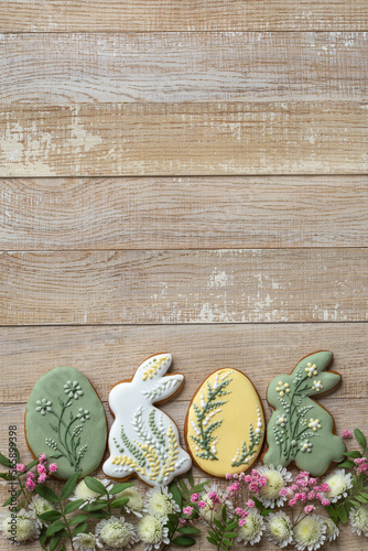 wooden background with easter icing cookies and flowers