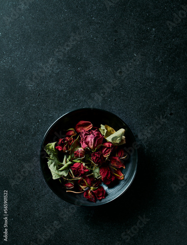 Dried red roses in a black ceramic bowl. Copy space