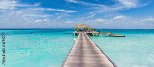 Tranquil Maldives island, luxury over water villas resort and wooden pier. Beautiful sunny sky. Sea bay lagoon beach background. Summer vacation holiday. Paradise shore exotic landscape, pristine blue