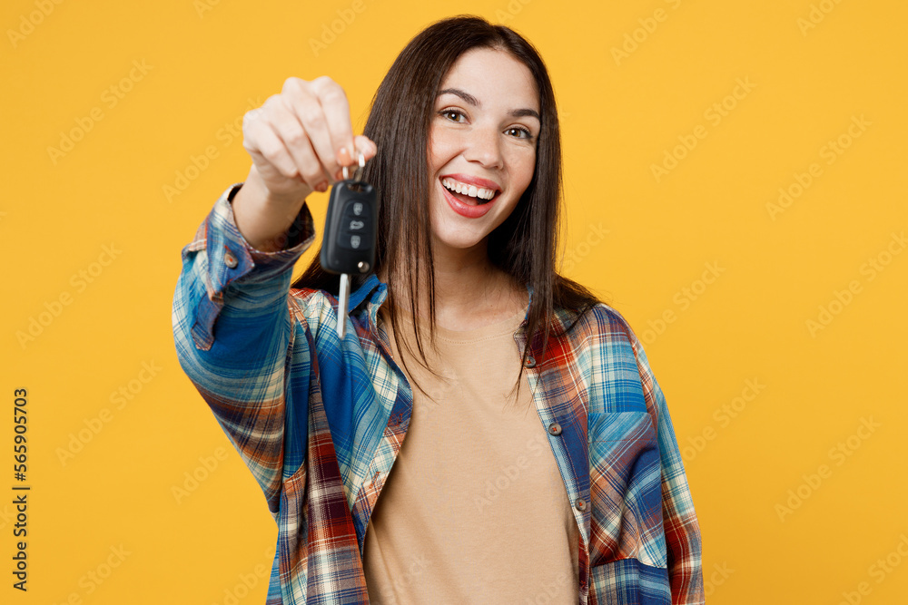 Young fun cmiling cheerful overjoyed excited woman wear blue shirt beige t-shirt hold in hand give key fob keyless system isolated on plain yellow background studio portrait. People lifestyle concept. Young fun cmiling cheerful overjoyed excited woman wear blue shirt beige t-shirt hold in hand give key fob keyless system isolated on plain yellow background studio portrait. People lifestyle concept.