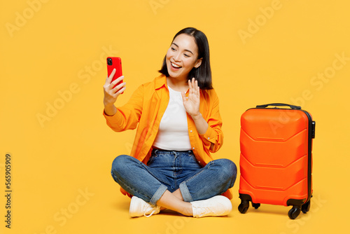 Young fun woman wear summer clothes sit suitcase do selfie shot mobile cell phone isolated on plain yellow background. Tourist travel abroad in free time rest getaway. Air flight trip journey concept. #565905909
