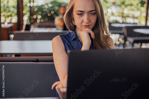 a girl sits on a summer terrace and works at a laptop. freelance. selfeducation. the concept of remote learning and outdoor work. photo