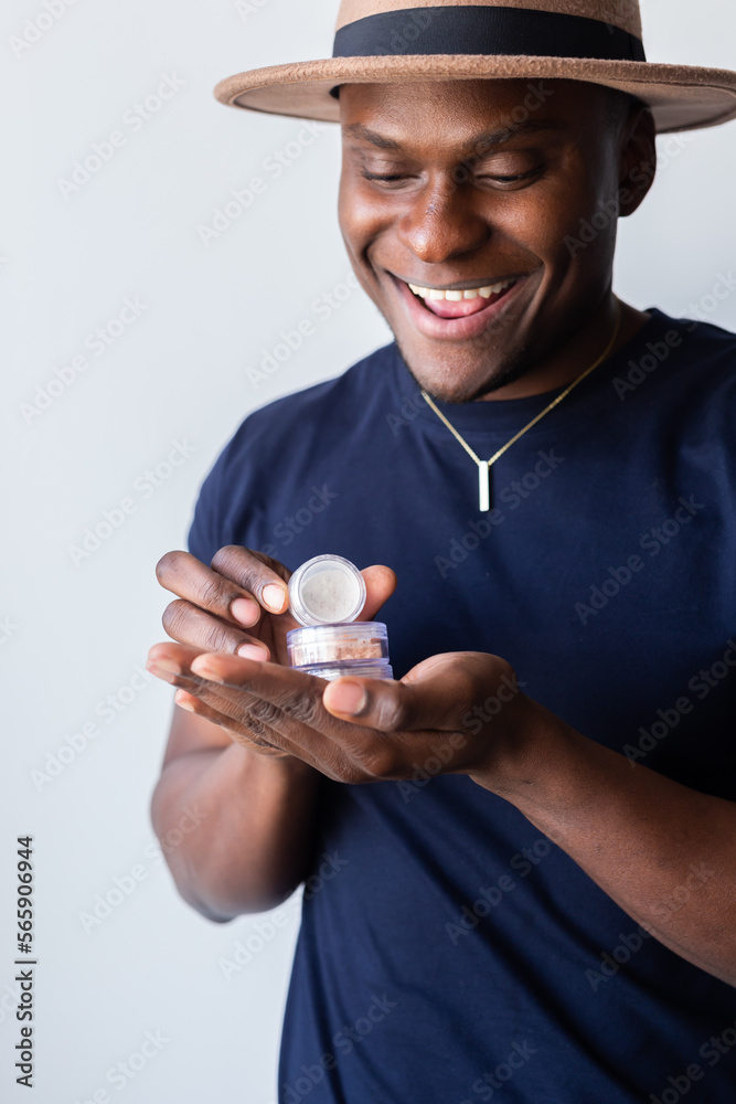 African american man holds mineral facial powder for perfect make-up for women - male make-up artist and cosmetic product concept African american man holds mineral facial powder for perfect make-up for women - male make-up artist and cosmetic product concept