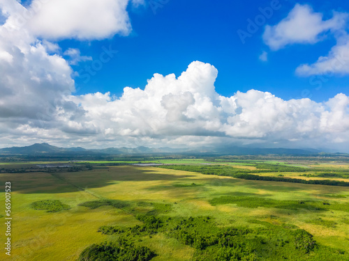 Aerial view of green meadows and mountains in the background and cloudy blue sky. The beautiful nature of the Dominican Republic