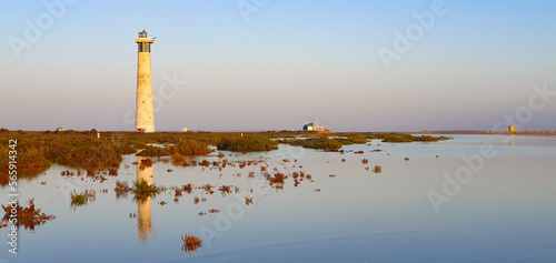 Lighthouse with water, salt marsh and reflection in foreground, Morro Jable, Jandia, Canary Islands photo