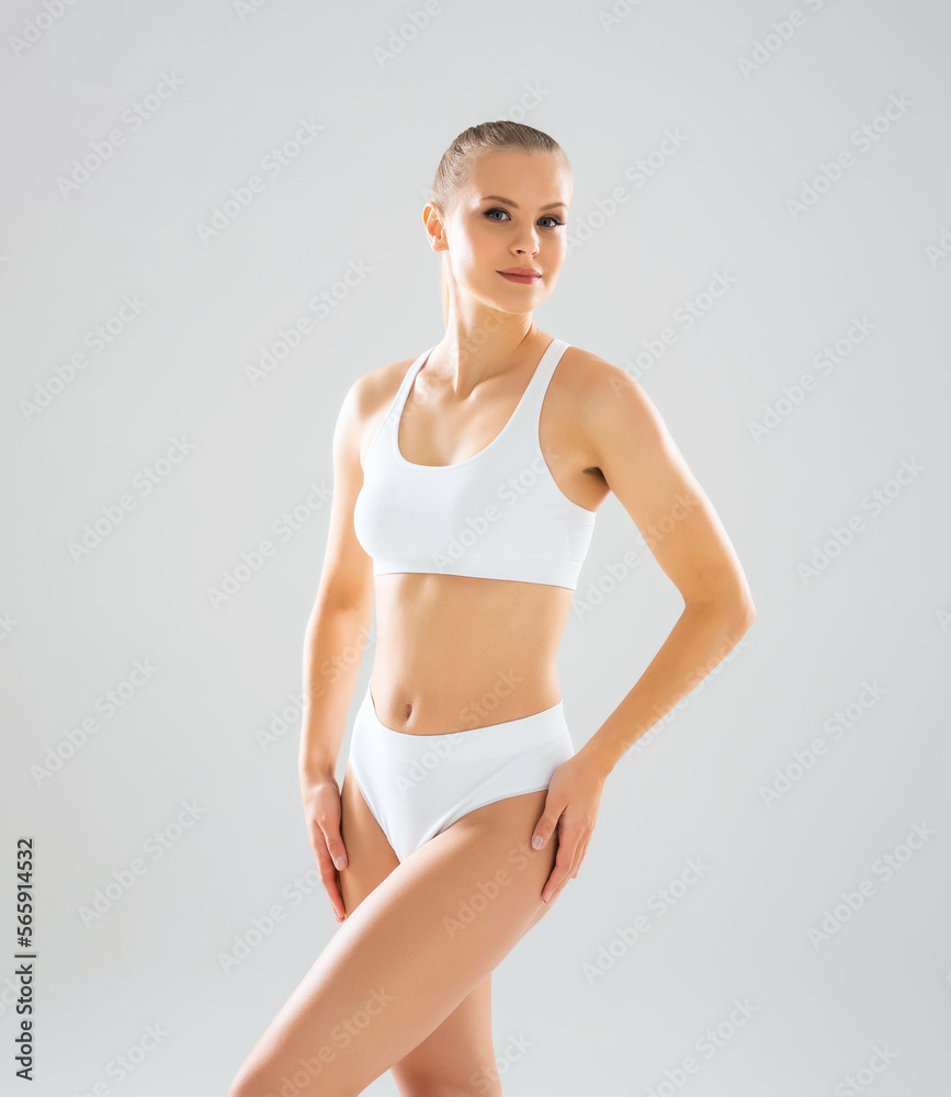 Young, fit and beautiful blond woman in white swimsuit isolated on grey background. Healthcare, diet, sport and fitness concept. Young, fit and beautiful blond woman in white swimsuit isolated on grey background. Healthcare, diet, sport and fitness concept.