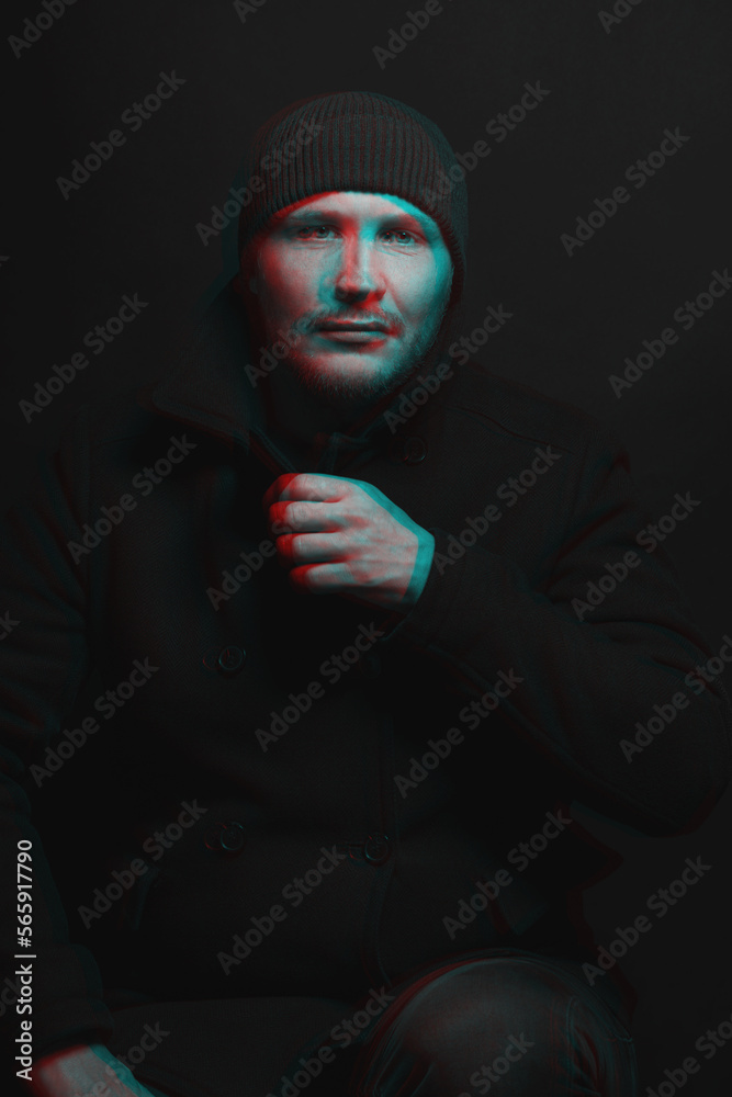 Lifestyle concept. Man with winter hat and black coat studio portrait. Model with beard looking at camera with serious look. Red and blue color split effect style. 3D glitch virtual reality effect Lifestyle concept. Man with winter hat and black coat studio portrait. Model with beard looking at camera with serious look. Red and blue color split effect style. 3D glitch virtual reality effect