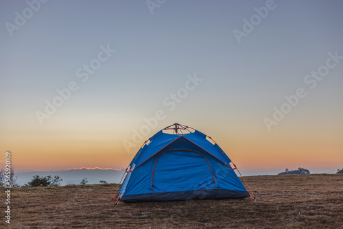 Blue camping tent on top of mountain with amazing sunrise on background. Time spending on fresh air. Travelling concept.