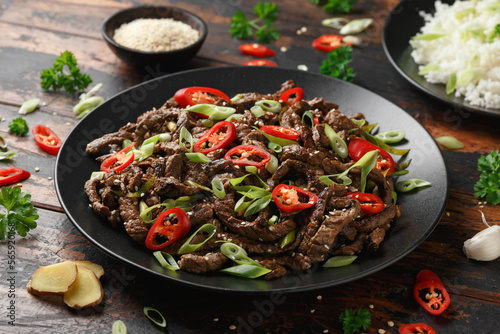 Korean beef Bulgogi with sesame seeds, chili and spring onion in a black plate