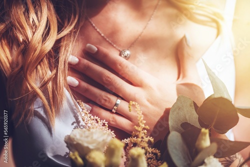 Close-up of bride holding her hand on heart, selective focus