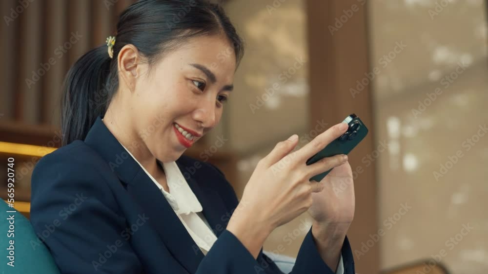 Youth Asia business female passenger wear suit sit on couch use smartphone chat, texting, booking online ticket in airline lounge wait for transit international airport. Travel business trip concept. Youth Asia business female passenger wear suit sit on couch use smartphone chat, texting, booking online ticket in airline lounge wait for transit international airport. Travel business trip concept.