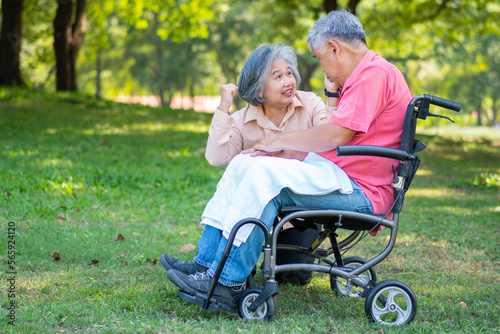 Senior couple in the park and wife taking care of a husband in a wheelchair a patient with paralysis, with his wife comforting and encouraging each other. Retirement health insurance concept. © Prot