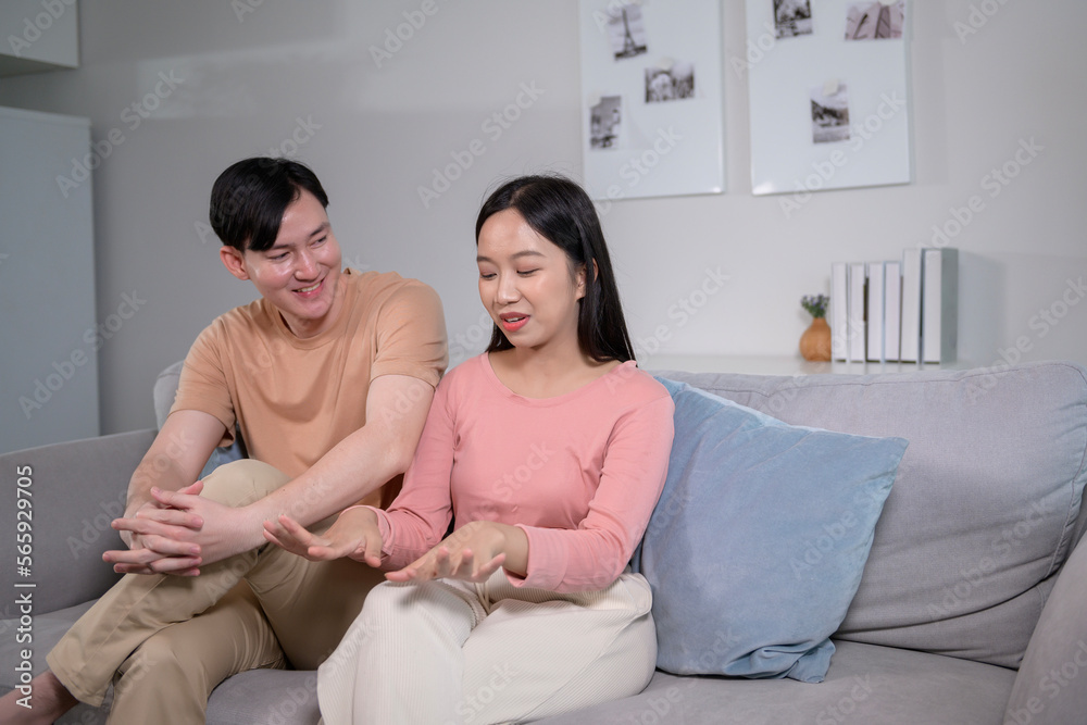 Happy young Asian couple sitting on sofa relaxing together in living room at home Happy young Asian couple sitting on sofa relaxing together in living room at home