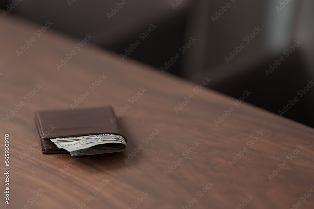 Full grain leather wallet with us dollars on walnut table Full grain leather wallet with us dollars on walnut table