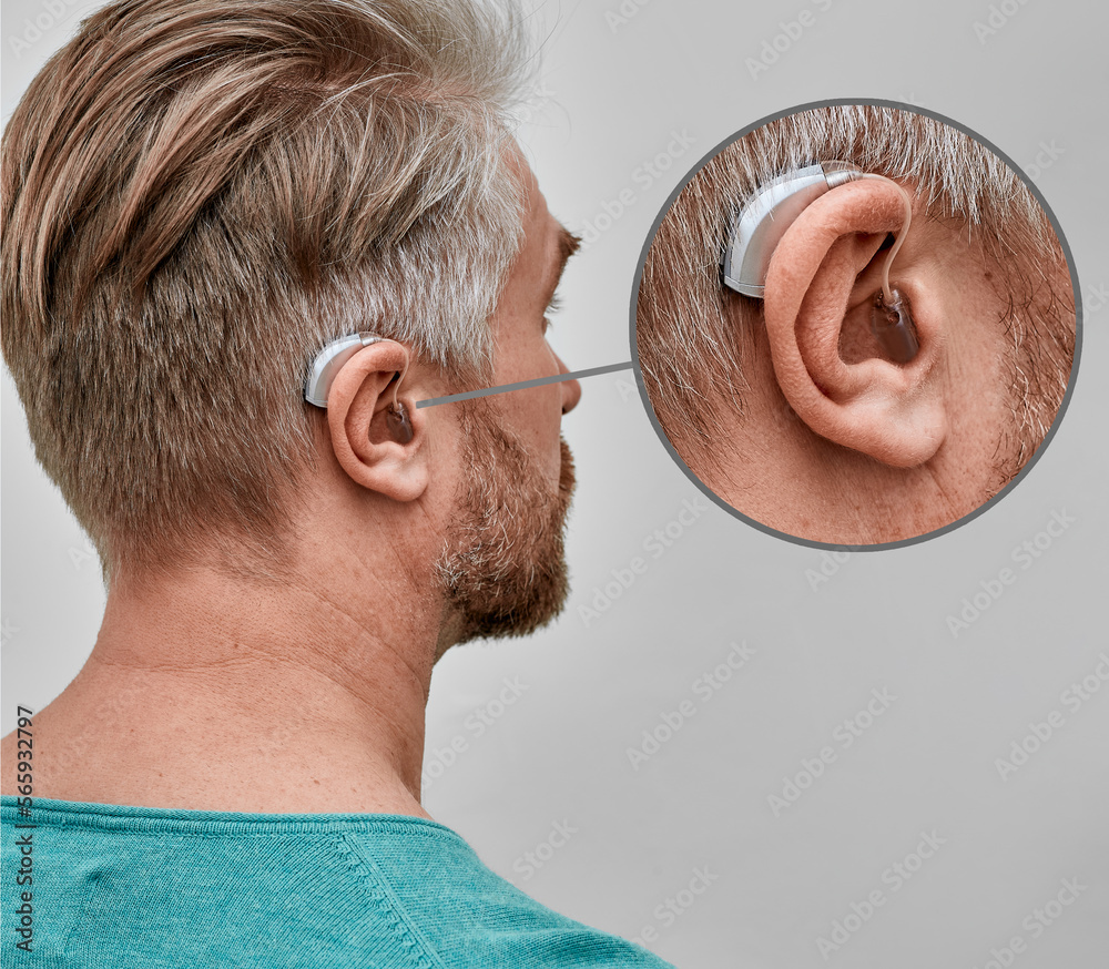 Improving hearing with hearing aids. Hearing aid behind the ear of adult man, closeup with