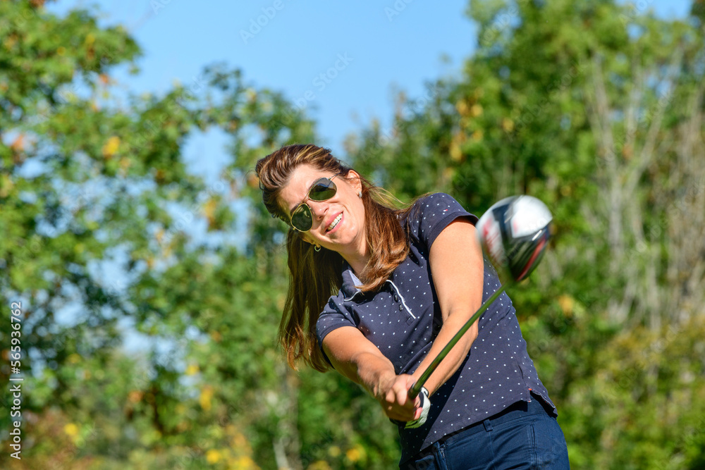 Golferin spielt einen Ball vom Tee mit dem Driver Golferin spielt einen Ball vom Tee mit dem Driver