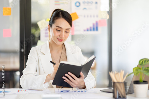 Asian Business woman using calculator and laptop for doing math finance on an office desk, tax, report, accounting, statistics, and analytical research concept 