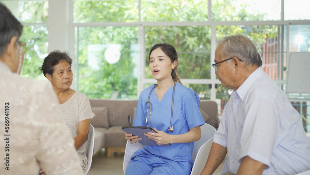 Obraz premium An Asian nurse talking to a group of old elderly patient or pensioner people smiling, relaxing, having fun together in nursing home. Senior lifestyle activity recreation. Retirement. Health care