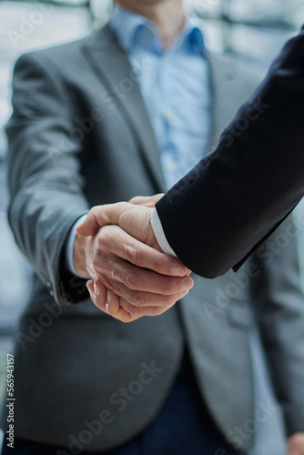 Two diverse professional business men executive leaders shaking hands at office meeting