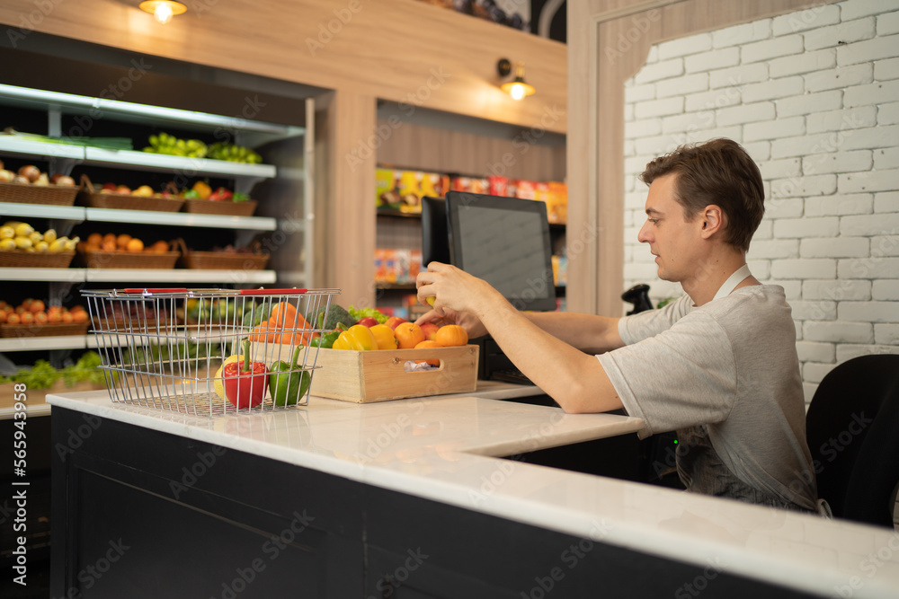 Portrait of a caucasian man working on cashier in a supermarket or retail shop, snacks and food on grocery products shelves. Food shopping. People lifestyle. Checkout business counter service. Worker