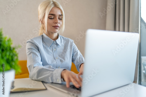 Young girl student or office worker at workplace behind laptop.