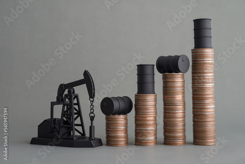 Crude oil tank on stack coin as price chart graph rising up and pump jack on grey background. World petroleum and energy industry or trading commodity investment, crude oil and gas price increase.