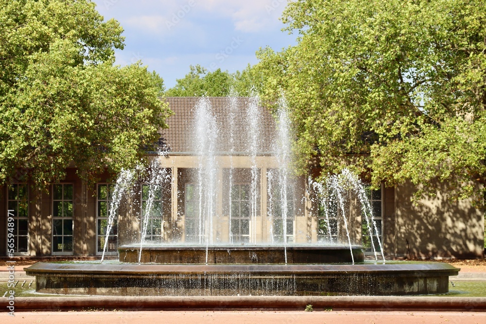 Water fountain in Dusseldorf Nordpark. Art centre 'Ballhaus im Nordpark' in the background.