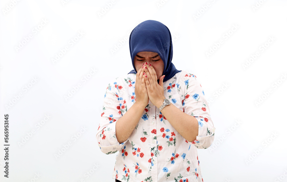 Asian muslim woman covering her nose while sneezing. Isolated on white background Asian muslim woman covering her nose while sneezing. Isolated on white background