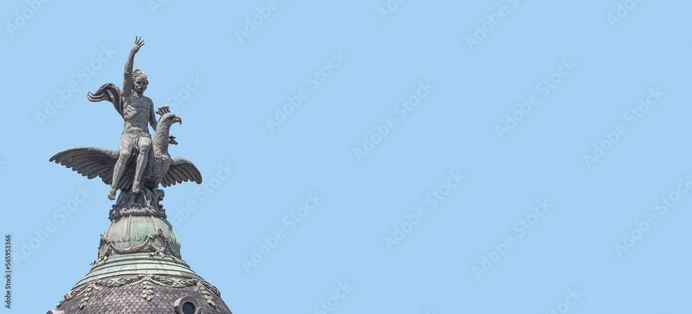 Banner with a top dome statue of a young man riding a big eagle in Barcelona historical downtown, Spain, at blue sky solid background with copy space